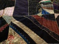 Close-up of patchwork fabric with multiple colors and hand stitching detail.