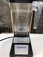 Front view of the Blendtec Home blender showing the clear blending container with measurement markings and the digital control buttons on the black base with the digital menu screen.