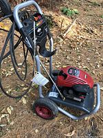 Side view of full power washer showing frame, wheels, engine, hose and wand