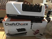 Electric knife sharpener on top of its original box showing branding and overall design