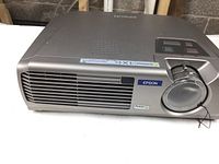 Front view of gray Epson PowerLite digital projector with lens cap on and visible vents.