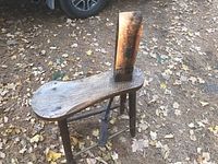 Full view of antique pony vice showing wooden bench with contoured top, three legs, and vertical clamping jaw.