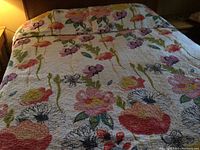 Full view of king size quilted bedspread with colorful floral pattern spread on bed.