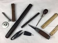 Metal bolt with disc, wooden burnishing rods, metal bar, snips and bone folders arranged on white background