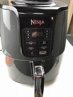Front view of black Ninja air fryer with digital control panel featuring cooking modes air fry, roast, reheat, and dehydrate.
