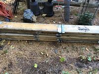 Folded wooden raised garden bed frame planks tied together with manufacturer label showing brand 'Turols'