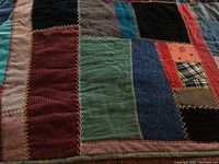 Close-up of quilt fabric patches showing various colors like green, red, blue, black and decorative zigzag stitching