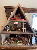 Full view of the wooden A-frame mouse house with multiple levels showing mice and furniture inside