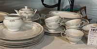 Photo of the full set showing plates, teacups, creamer, sugar bowl, and serving bowl on table.