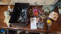 Full view of all items on wooden table showing jewelry, dolls, watches, and boxed Star Trek figurines
