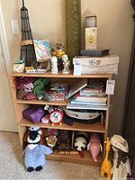 Shelf with assorted figurines, collectibles, boxes, books, plush items, and a decorative Eiffel Tower figure.