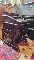 Front and side view of the vintage writing desk showing carved scroll legs and eight drawers