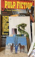 Wide view showing Pulp Fiction movie poster on cardboard backing and two original paintings leaning against it.