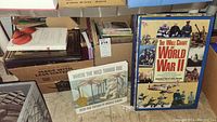 Box containing various books with some titles visible including 'Where the Wild Things Are' book and boxed books.