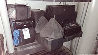 Shelf holding multiple black Sony and RCA speakers and an RCA labeled audio electronic unit with visible buttons and a blue cable coiled on the front.