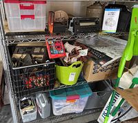 Full view of metal shelving with all lot contents including storage bins, car radio, oil cans, and Intellivision parts