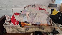 Top view showing multiple vintage quilts in various patchwork styles inside a plastic storage bin.