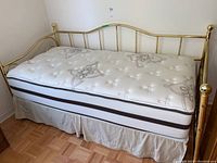 Full view of metal framed day bed with Beautyrest mattress showing the gold frame and mattress patterned top.