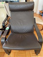 Front view of IKEA Poang chair showing brown leather upholstery and wooden arms.