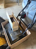 Yardworks electric dethatcher in a cardboard box, showing the detached handle and motor unit.