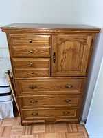 Front view of the dresser showing three smaller drawers stacked vertically on left and one paneled door on right, with two larger drawers below all fitted with brass handles.