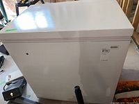 White Kenmore chest freezer, closed, showing exterior front with Kenmore label and sticker.