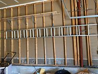 Photo of full ladder hung on garage wall showing length and frame structure