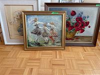 Three framed artworks together: watercolour painting of white lilies, hand-painted canvas of three dancing girls, framed cross stitch of red poppies.