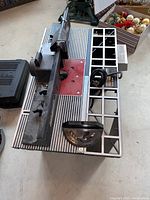 Full view of router table work surface showing metal table top with router insert plate and adjustable fence with locking knobs and circular guide