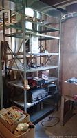 Front view of metal utility shelving unit in basement environment, showing six metal shelves with various items but contents not included in sale