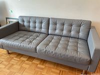 Front view of sofa showing tufted grey leather upholstery and chrome legs