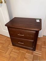 Front view of the wood side table showing two drawers with brass handles and dark brown finish.