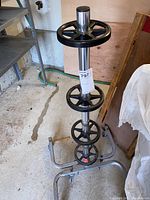 Full view of metal tire stand showing stacked black wheel holders on a vertical pole and wheeled base.