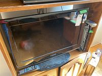 Samsung 26 inch flatscreen TV on stand with remote in front. Model label visible on TV's lower bezel.