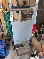 Full view of the front side of the utility vehicle showing the gray metal frame with rollers and black wheels.