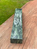 Top view of rectangular jade scroll weight carved with mountainous and botanical designs, showing engraved signature.