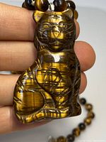 Close-up view of the carved tigers eye cat pendant showing detailed carving and polished surface.
