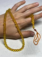 Overall view of antique amber prayer beads being held in hand to show size and color.