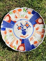 Top view of the circular Imari porcelain charger showing vibrant blue, orange, and reddish-brown decoration with scalloped edge.