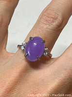 Front view of the sterling silver ring worn on finger showing oval lavender jade stone and accent stones on each side.