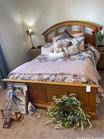 Full view of bed frame with bedding, showing headboard, footboard, and assorted pillows and comforters