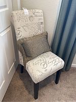 Side chair upholstered with postcard and script graphics fabric, shown with decorative throw pillow.