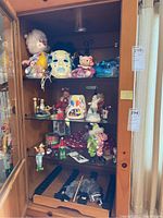 Wide shot of cabinet showing various clown figurines on shelves including dolls, masks, and decorations