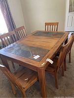 Full view of oak dining table with stone tile inlays and six matching oak chairs around it.