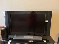 Philips flat screen TV with a 37-inch screen size placed on a black surface, showing the front view of the TV screen and frame. A small black fan is beside the TV but is not included in the sale.