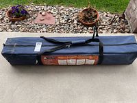 Blue zippered carrying case with handles containing the folded gazebo parts.