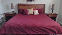Overall front view of the solid wood king size bedframe dressed with red bedding and decorative pillows