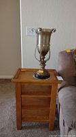 Solid wood side table with decorative table lamp on top, shown next to sofa.