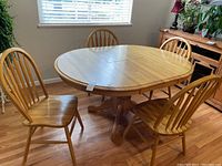 Dining table and four chairs in oak wood set, showing natural wood finish and design.