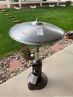 Full view of propane patio heater showing large metallic dome heat reflector on top, central support column and base.